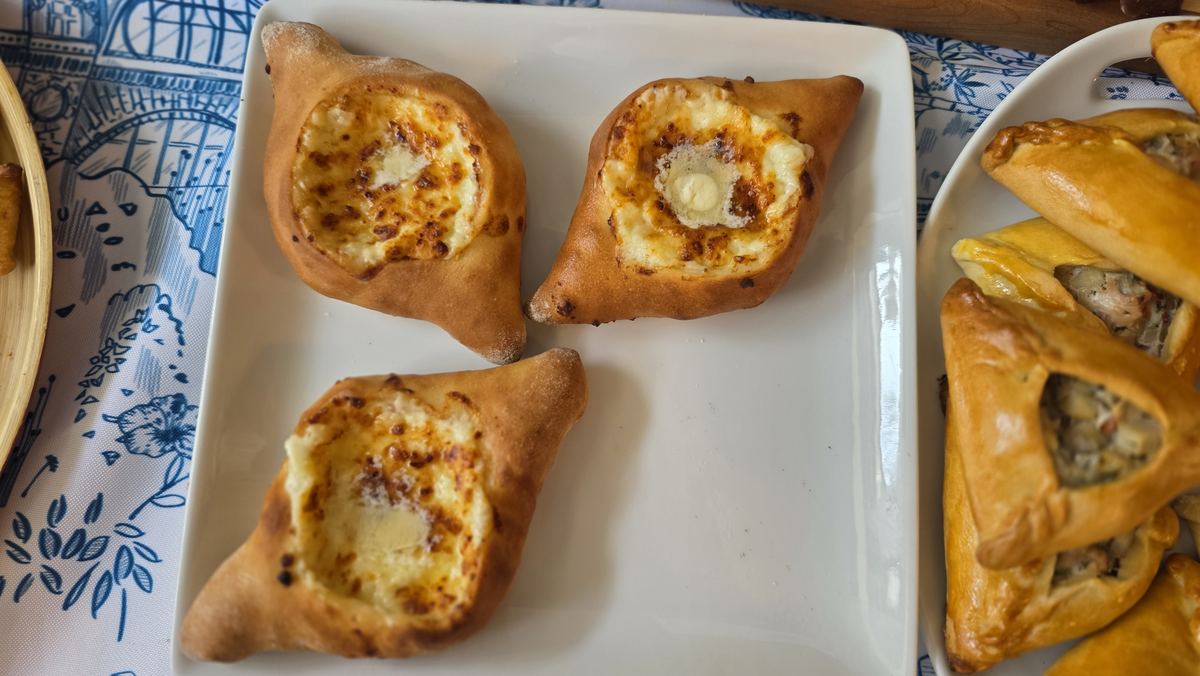 Freshly baked Georgian cheese boats on a blue and white plate at Kolhelly Bakery in Brooklyn